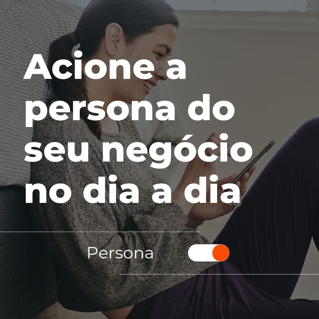 #PraCegoVer: a imagem mostra uma mulher branca sorrindo e mexendo no celular enquanto está sentada no chão, apoiando suas costas em uma cama. Em cima da fotografia está escrito: "Acione a persona do seu negócio no dia a dia".